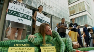 Animal rights activists painted in crocodile print rally outside the Hermes Tokyo store to protest the luxury brand's use of exotic animal skins for their bags. (Photo grabbed from Reuters video/Courtesy Reuters)