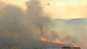 A helicopter flies over the raging bushfire in Australia's Blue Mountains.  (Photo grabbed from Reuters video)