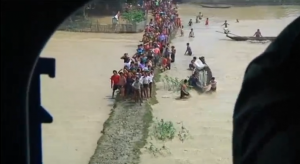 People affected by Myanmar's extensive floods wait for relief to arrive as a helicopter carrying food hovers by.  (Photo grabbed from Reuters video) 