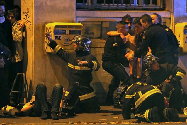 French fire brigade members aid an injured individual near the Bataclan concert hall following fatal shootings in Paris, November 13, 2015. REUTERS/Christian Hartmann