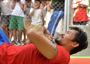 This photo taken on February 16, 2016 shows schoolchildren watching as Philippine boxing icon Manny Pacquiao (bottom) works out during a training session at a sports complex in General Santos on the southern Philippine island of Mindanao in preparation for his bout with Timothy Bradley in the US in April. Pacquiao has opened the door to a lucrative rematch with Floyd Mayweather, telling AFP he still intends to retire after his next fight but that a comeback is possible.      AFP PHOTO / TED ALJIBE 