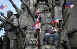 TO GO WITH Philippines-revolution-vote-Marcos-rights,FOCUS by Joel Guinto Renato Vallarte (top C), a worker from the Spirit of EDSA Foundation, attaches flags to the statues at the People Power Monument two days before the anniversary of the People Power revolution in Manila on February 23, 2016. The Philippines is this week celebrating 30 years of democracy, but thousands who suffered through the Marcos dictatorship tremble with anger at slow justice and the stunning political ascent of the late strongman's heir. President Benigno Aquino will on February 25 lead the commemoration of the "People Power" uprising that allowed his mother, Corazon, to take over from Ferdinand Marcos after he fled to the United States. AFP PHOTO / NOEL CELIS / AFP / NOEL CELIS