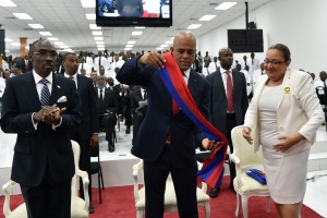 Haitian President, Michel Martelly(C) take his presidential sash before to deliver to Jocelerme Privert(C) President of National Assambly during the ceremony in the Haitian Parliament February 7, 2016 in Port-au-Prince where Martelly gave his last address to the nation before stepping down as president. Haitian politicians inked a last-minute agreement to install a transitional government February 6, just hours before President Michel Martelly was scheduled to step down with no replacement in line. / AFP / HECTOR RETAMAL