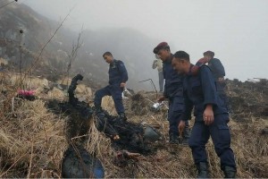 Nepalese authorities inspect a burned body near the wreckage of a plane operated by Tara Air. (Photo from Reuters/Santosh Gautam)