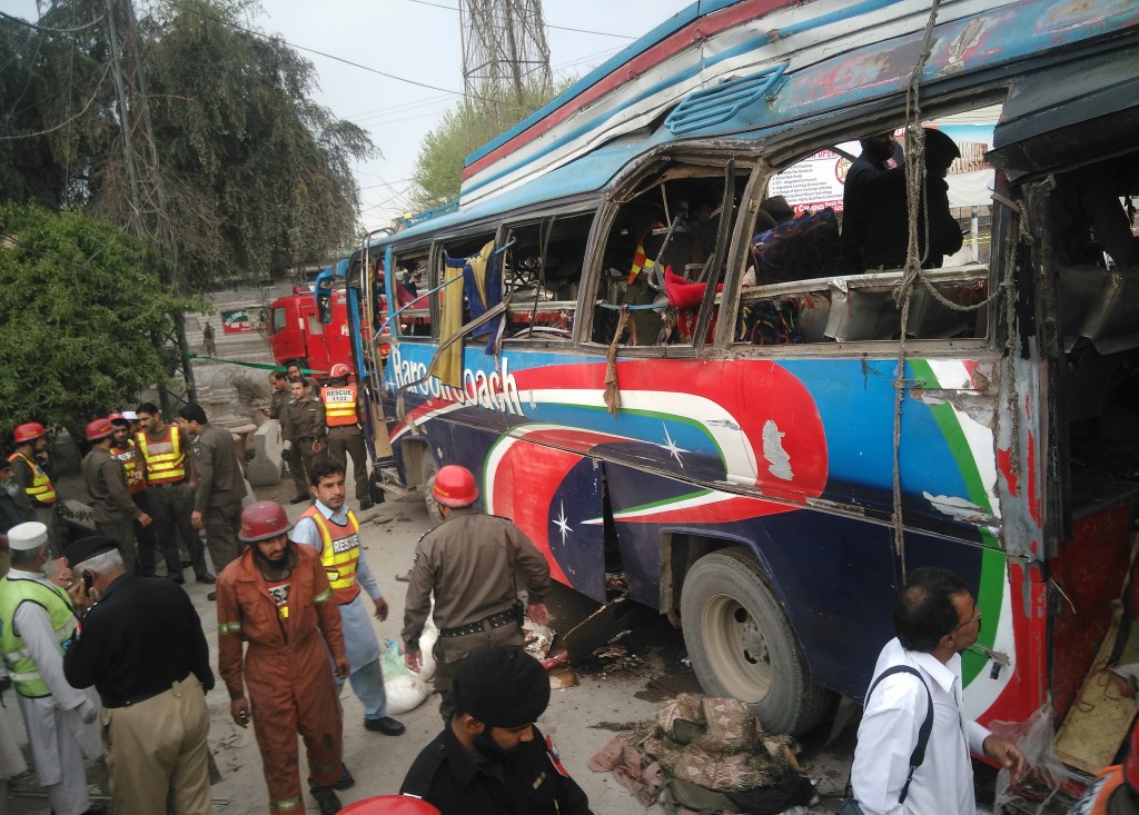 Pakistani police officials search a damaged bus after a bomb blast in Peshawar on March 16, 2016. A blast ripped through a bus carrying government employees on March 16 killing at least 10 and wounding 27 another in Peshawar, northwestern Pakistan, officials said. / AFP / A MAJEED
