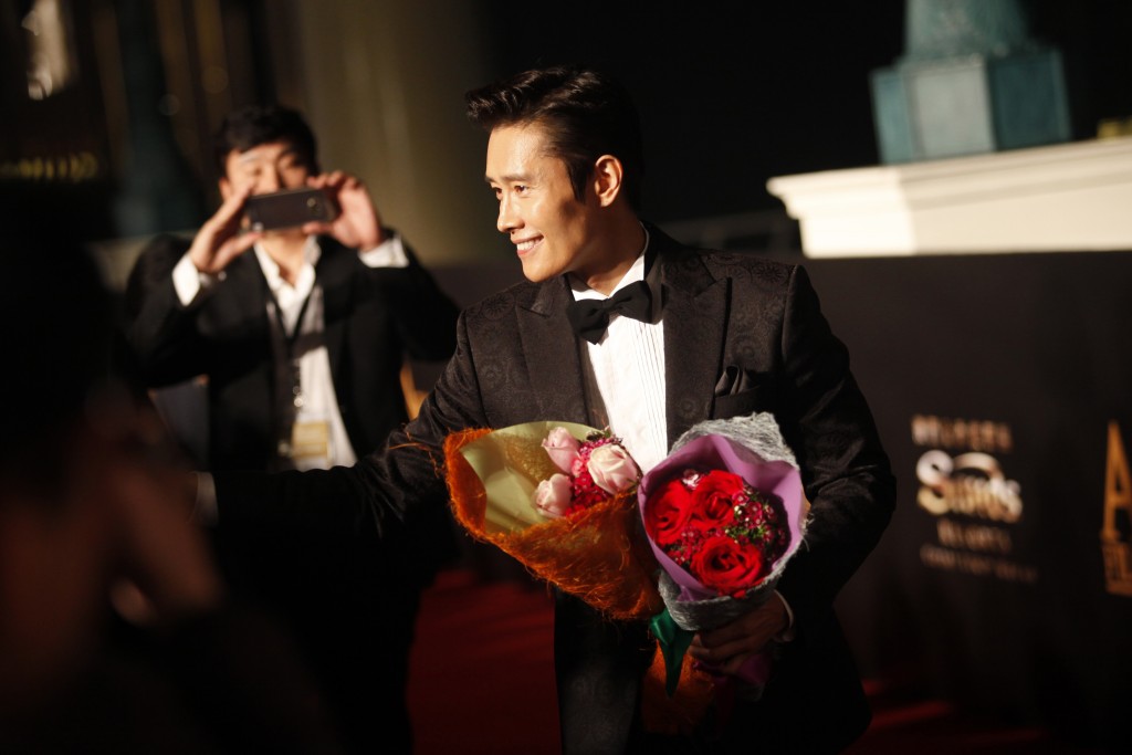 Lee Byung-hun (R) walks  the red carpet at the Asian Film Awards in Macau on March 17, 2016. Movie stars attended the event held annually since 2007, aimed at showcasing the region's movie talent. / AFP / ISAAC LAWRENCE