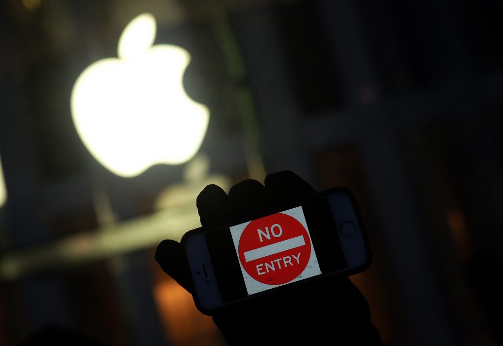 An anti-government protester holds up his iPhone with a sign "No Entry" during a demonstration near the Apple store on Fifth Avenue in New York on February 23, 2016. Apple is battling the US government over unlocking devices in at least 10 cases in addition to its high-profile dispute involving the iPhone of one of the San Bernardino attackers, court documents show. Apple has been locked in a legal and public relations battle with the US government in the California case, where the FBI is seeking technical assistance in hacking the iPhone of Syed Farook, a US citizen, who with his Pakistani wife Tashfeen Malik in December gunned down 14 people. / AFP PHOTO / Jewel Samad
