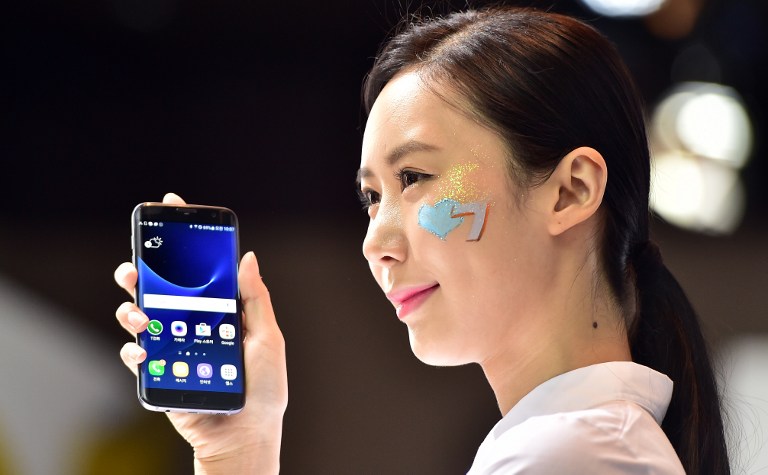 A South Korean woman holds up Samsung Electronics' latest flagship smartphone, the Galaxy S7 edge, during a showcase to mark the domestic launch in Seoul on March 10, 2016. Sales of the Galaxy S7 and S7 edge begin in around 60 countries on March 11. / AFP PHOTO / JUNG Yeon-Je