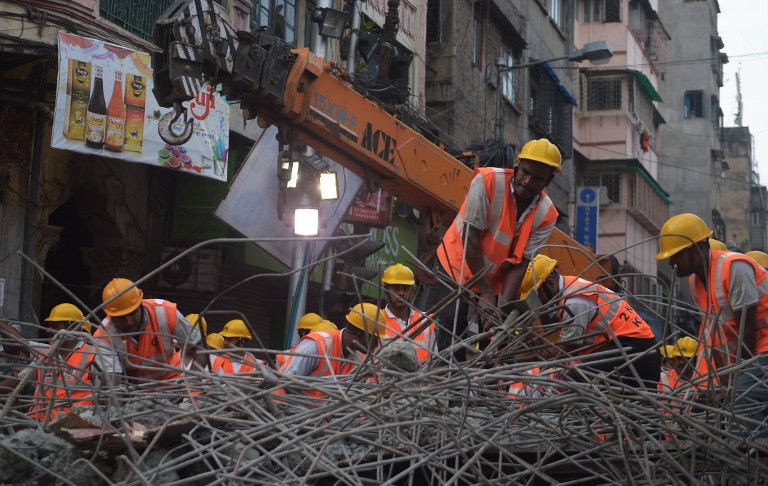 Indian rescue workers try to free people trapped under the wreckage of a collapsed flyover bridge in Kolkata on April 1, 2016. Emergency workers in India battled to rescue dozens of people still trapped after a flyover collapsed onto a busy street, killing at least 22 people and injuring over 100 more. / AFP / Dibyangshu SARKAR