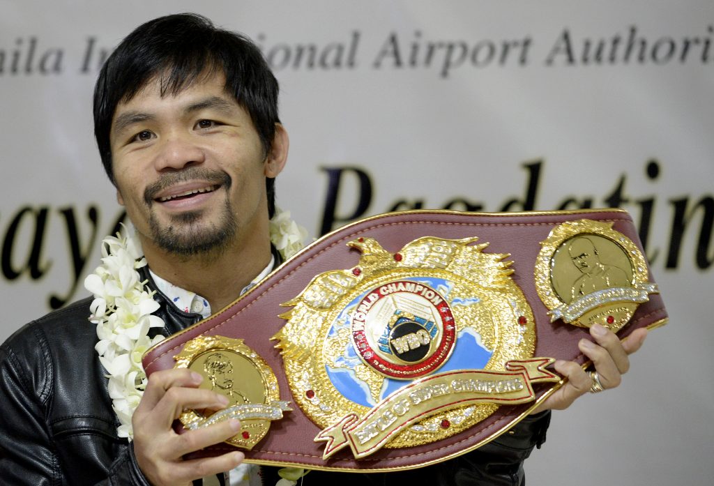 Filipino boxer Manny Pacquiao holds his championship belt as he arrives at the Manila International Airport in Manila on April 14, 2016. Pacquiao defeated Timothy Bradley Jr. of the US in Las Vegas, Nevada on April 10, 2016. / AFP PHOTO / NOEL CELIS