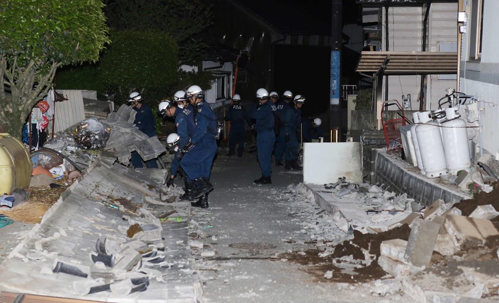 Police officers search for victims under collapsed stone walls in the town of Mashiki, Kumamoto prefecture, early on April 15, 2016, after strong 6.4-magnitude earthquake hit Japan's southwestern island of Kyushu the day before. Nine people were killed after a powerful earthquake hit southern Japan, collapsing homes, sparking fires and injuring hundreds, officials said on April 15 as rescuers worked through the night to find residents feared trapped in rubble. / AFP PHOTO / JIJI PRESS / JIJI PRESS / Japan OUT / JAPAN OUT
