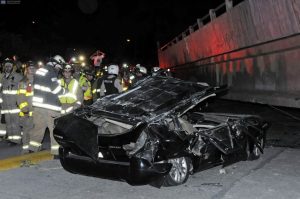 Rescue workers stand before a destroyed car after the collapse of a bridge in an earthquake, April 16, 2016 in Guayaquil, Ecuador. At least 28 people were killed by a strong 7.8-magnitude earthquake that struck northwestern Ecuador, the country's Vice President Jorge Glas said. A tate of emergency had been declared nationwide. / AFP PHOTO / MARCOS PIN MENDEZ