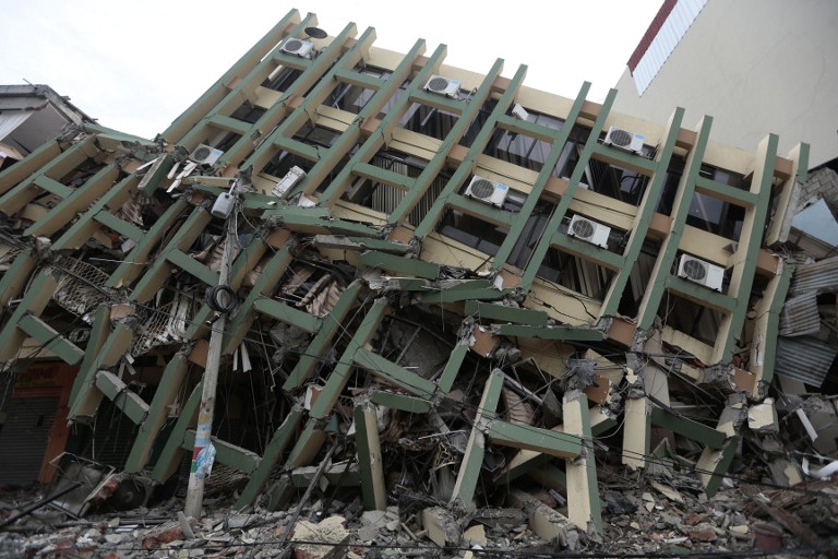 View of a fallen building after a 7.8-magnitude quake in Portoviejo, Ecuador on April 17, 2016. At least 77 people were killed when a powerful earthquake struck Ecuador, destroying buildings and a bridge and sending terrified residents scrambling from their homes, authorities said Sunday. / AFP PHOTO / JUAN CEVALLOS
