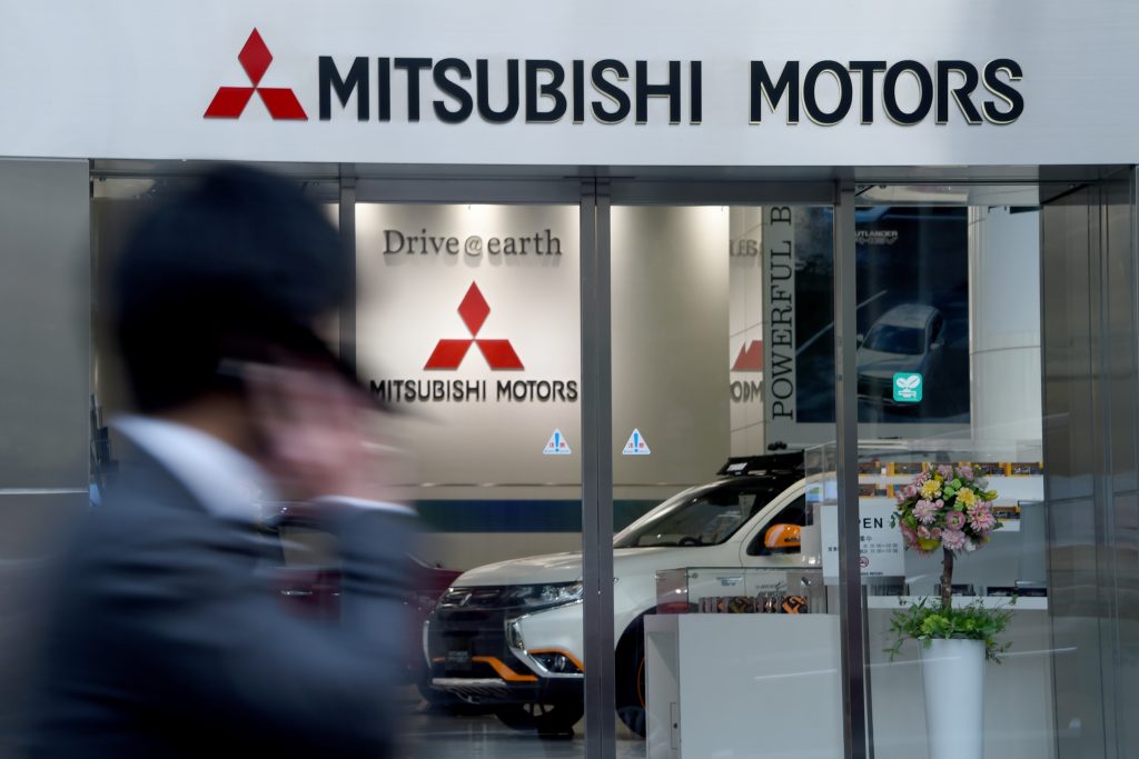 A businessman walks past the Mitsubishi Motors headquarters in Tokyo on April 20, 2016. Japanese automaker Mitsubishi on April 20 admitted it manipulated pollution data in more than 600,000 vehicles, after reports of misconduct sent its Tokyo-listed shares plummeting earlier in the day. / AFP PHOTO / TOSHIFUMI KITAMURA