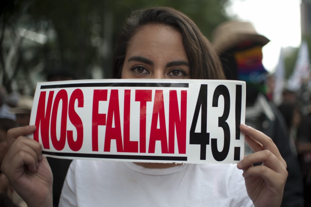 A woman holds a sign reading "We are missing 43" as the parents of 43 missing students from Ayotzinapa teachers school march 18 months after their disappearance in Mexico City on April 26, 2016. / AFP PHOTO / YURI CORTEZ