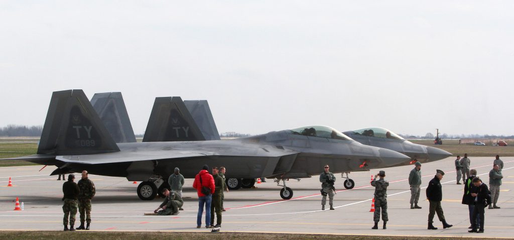People stand next to two US Air Force F-22 Raptor fighter aircraft at the Air Base of the Lithuanian Armed Forces in iauliai, Lithuania, on April 27, 2016.  / AFP PHOTO / Petras Malukas