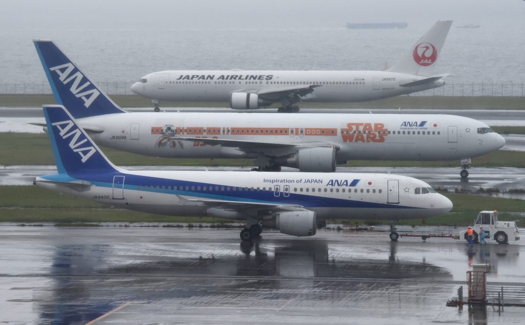 Japan Airlines (JAL/top) and All Nippon Airways (ANA) aircraft are seen at Haneda Airport in Tokyo on April 28, 2016.  The Japan's two-biggest airlines will announce their financial results for fiscal year 2015 ended March 2016. / AFP PHOTO / TORU YAMANAKA