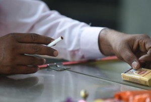 An Indian smoker purchases a single cigarette from a roadside shop in New Delhi on November 26, 2014. Health campaigners welcomed India's plans to raise the age for tobacco purchases to 25 and ban unpackaged cigarettes, hailing them as a major step towards stopping nearly one million tobacco-related deaths a year. AFP PHOTO/ Prakash SINGH 