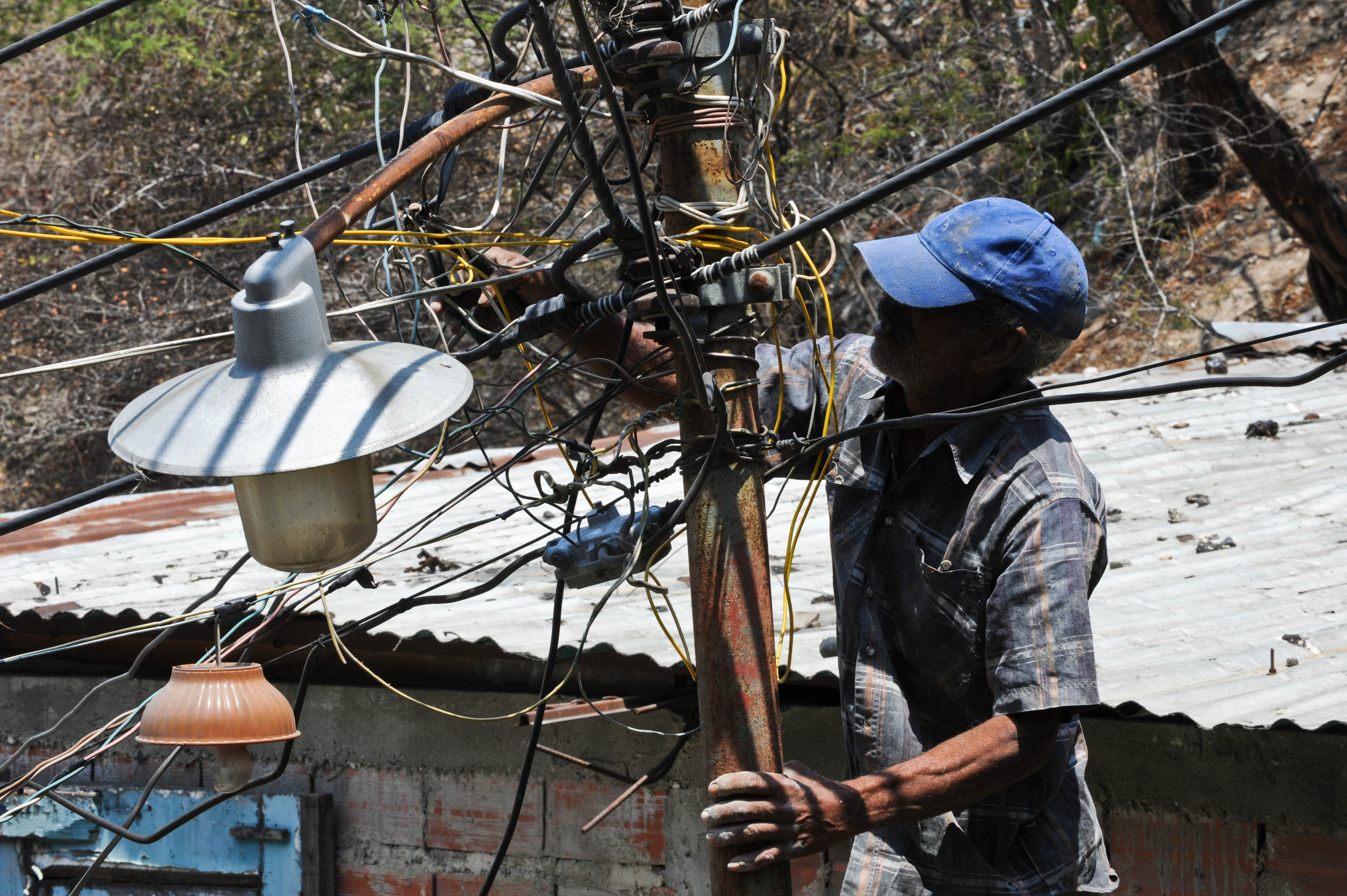 A man illegally wires his house to the public network, in Caracas, March 4, 2010. The Venezuelan government since last February enforces a policy of power comsumption reduction to face the power crisis, punishing those consumers who do not reduce their power consumption in at least 20 percent. . AFP PHOTO / Miguel GUTIERREZ / AFP PHOTO / MIGUEL GUTIERREZ