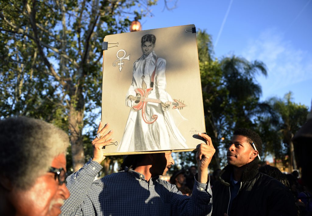 LOS ANGELES, CA - APRIL 21: A man holds a painting of Prince as he arrives to a celebration of musician Prince's life in Leimert Park on April 21, 2016, in Los Angeles, California. Prince died earlier today at his Paisley Park compound at the age of 57.   Kevork Djansezian/Getty Images/AFP