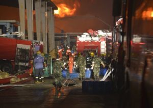 Firefighters and paramilitary policemen carrying goods near a site of an explosion in Taizhou (Photo from Reuters)