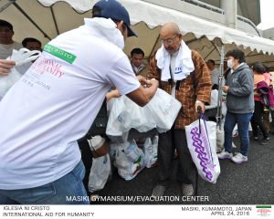 An old resident receives relief packs from an Iglesia Ni Cristo volunteer outside the Mashiki evacution center in Kumamoto, Japan. (Photo courtesy FYM Foundation)