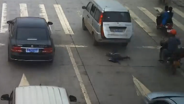 A young Chinese child has narrowly escaped death after falling out of the rear door of a moving minivan and being run over by a car.(photo grabbed from Reuters video) 