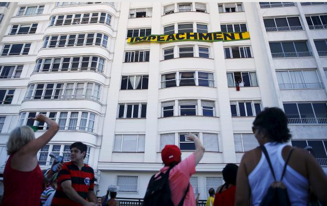 People walk in front of a sign that reads: 'Impeachment' in Copacabana beach in Rio de Janeiro, Brazil April 17, 2016. Reuters/Pilar Olivares