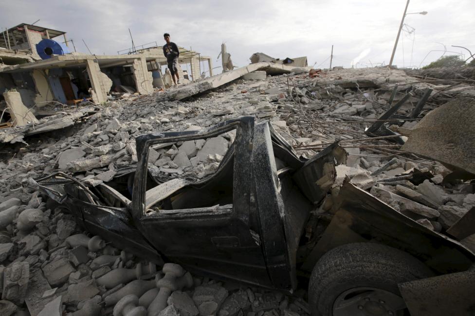 A flattened car is seen under the debris of a collapsed building, after an earthquake struck off the Pacific coast, in town of Canoa, Ecuador. REUTERS/Henry Romero