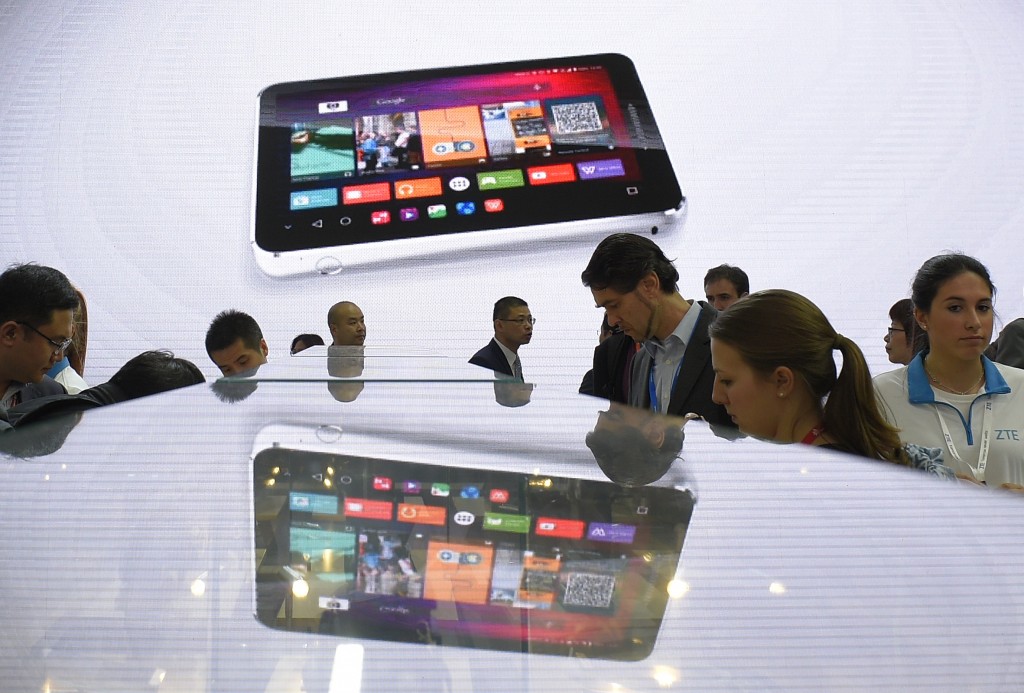 Visitors look at smartphones at the ZTE's stand on the second day of the Mobile World Congress in Barcelona on February 23, 2016. The world's biggest mobile fair, held from February 22 to February 25. / AFP PHOTO / LLUIS GENE