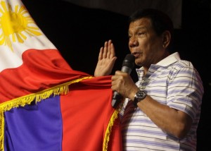 This photo taken on April 19, 2016 shows Rodrigo Duterte, front-runner presidential candidate for the May 9 elections, swearing in front of a national flag and supporters (not pictured) during a campaign sortie in Iloilo City, central Philippines. 