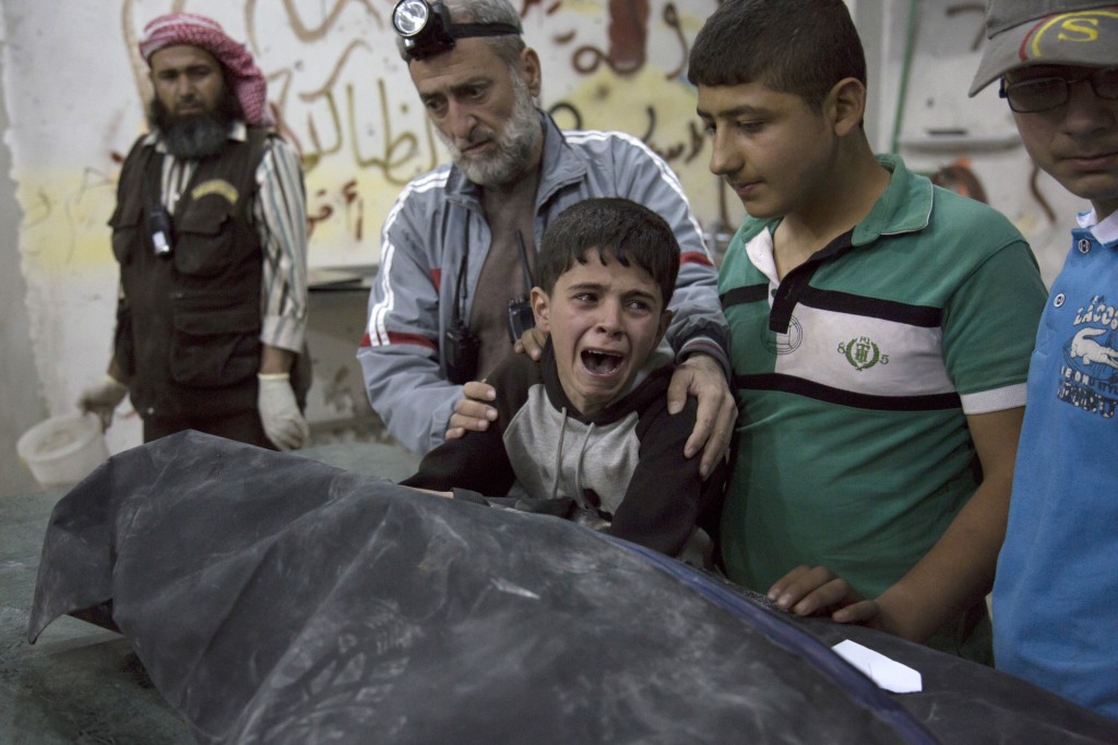 A Syrian boy is comforted as he cries next to the body of a relative who died in a reported airstrike on April 27, 2016 in the rebel-held neighbourhood of al-Soukour in the northern city of Aleppo. / AFP PHOTO / KARAM AL-MASRI