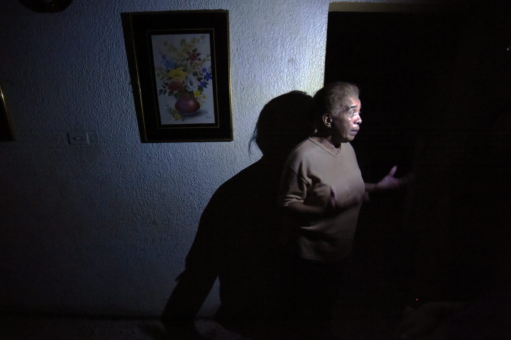 A woman talks inside her house during a power cut in Maracaibo city on April 28, 2016. The political tension, shortages and now enforced electricity blackouts that started this week have has raised fears of unrest in the South American oil state. Looting and clashes were reported in various towns including the country's second-biggest city Maracaibo after daily power cut-offs were formally launched on Monday. / AFP PHOTO / JUAN BARRETO