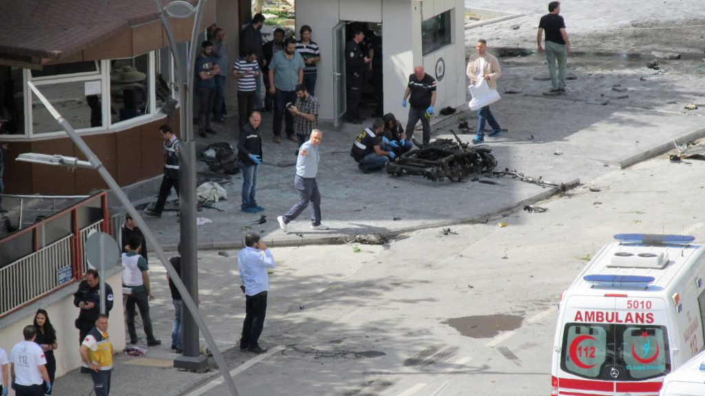 Police officers look at a piece of debris outside the police headquarters in the southeastern Turkish city of Gaziantep on May 1, 2016 after a bomb exploded, killing one police officer. A bomb exploded on May 1 outside police headquarters in the southeastern Turkish city of Gaziantep close to the Syrian border, killing one police officer and wounding 13 other people, the local governor said. Gaziantep regional governor Ali Yerlikaya was quoted by Turkish media as saying nine of those wounded were police. NTV television said the explosion was caused by a car bomb and had been followed by sounds of gunfire. / AFP PHOTO / ILHAS NEWS AGENCY / - / Turkey OUT