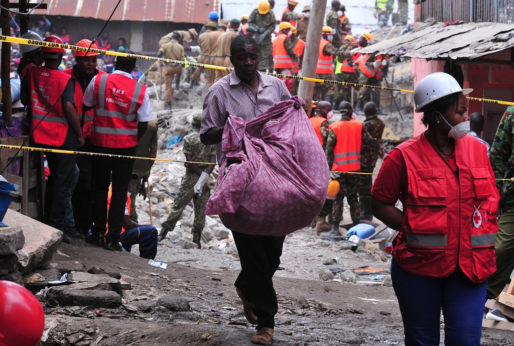 A man carries his belongings as he evacuates on May 3, 2016 the rubble of the six-storey building that collapsed killing 23 people in Nairobi's suburb of Huruma. Kenyan rescuers pulled an 18-month-old toddler alive from the rubble of a six-storey building on May 3, four days after the block collapsed killing 23 people, police said. Located in the poor, tightly-packed Huruma neighbourhood, the building had been slated for demolition after being declared structurally unsound. But an evacuation order for the structure, which was built near a river just two years ago, was ignored. / AFP PHOTO / SIMON MAINA