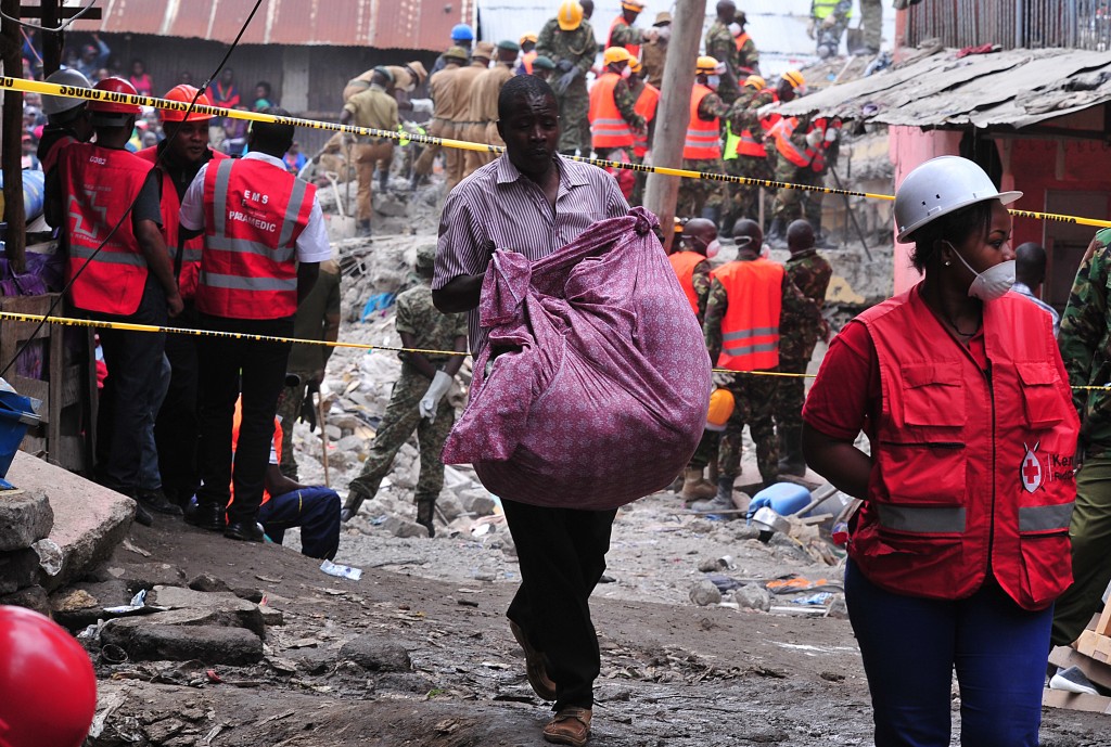 A man carries his belongings as he evacuates on May 3, 2016  the rubble of the six-storey building that collapsed killing 23 people in Nairobi's suburb of Huruma. Kenyan rescuers pulled an 18-month-old toddler alive from the rubble of a six-storey building on May 3, four days after the block collapsed killing 23 people, police said. Located in the poor, tightly-packed Huruma neighbourhood, the building had been slated for demolition after being declared structurally unsound. But an evacuation order for the structure, which was built near a river just two years ago, was ignored.   / AFP PHOTO / SIMON MAINA