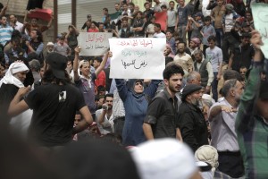 A woman holds a placard during a demonstration calling on all rebel-factions to end the fight and stop the killings in Aleppo, in the town of Mesraba in the eastern Ghouta region, a rebel stronghold east of the Syrian capital Damascus, on May 3, 2016. The writing in Arabic reads (R to L): "Our mujahideen brothers, Ghouta is one, we refuse to divide it", "Stop the fighting, we're on the same boat".    Russia said Tuesday it hoped a new ceasefire could be announced within hours for Syria's battered city of Aleppo, where fresh fighting left at least 16 dead including in rocket fire on a maternity hospital. / AFP PHOTO / ABDULMONAM EASSA