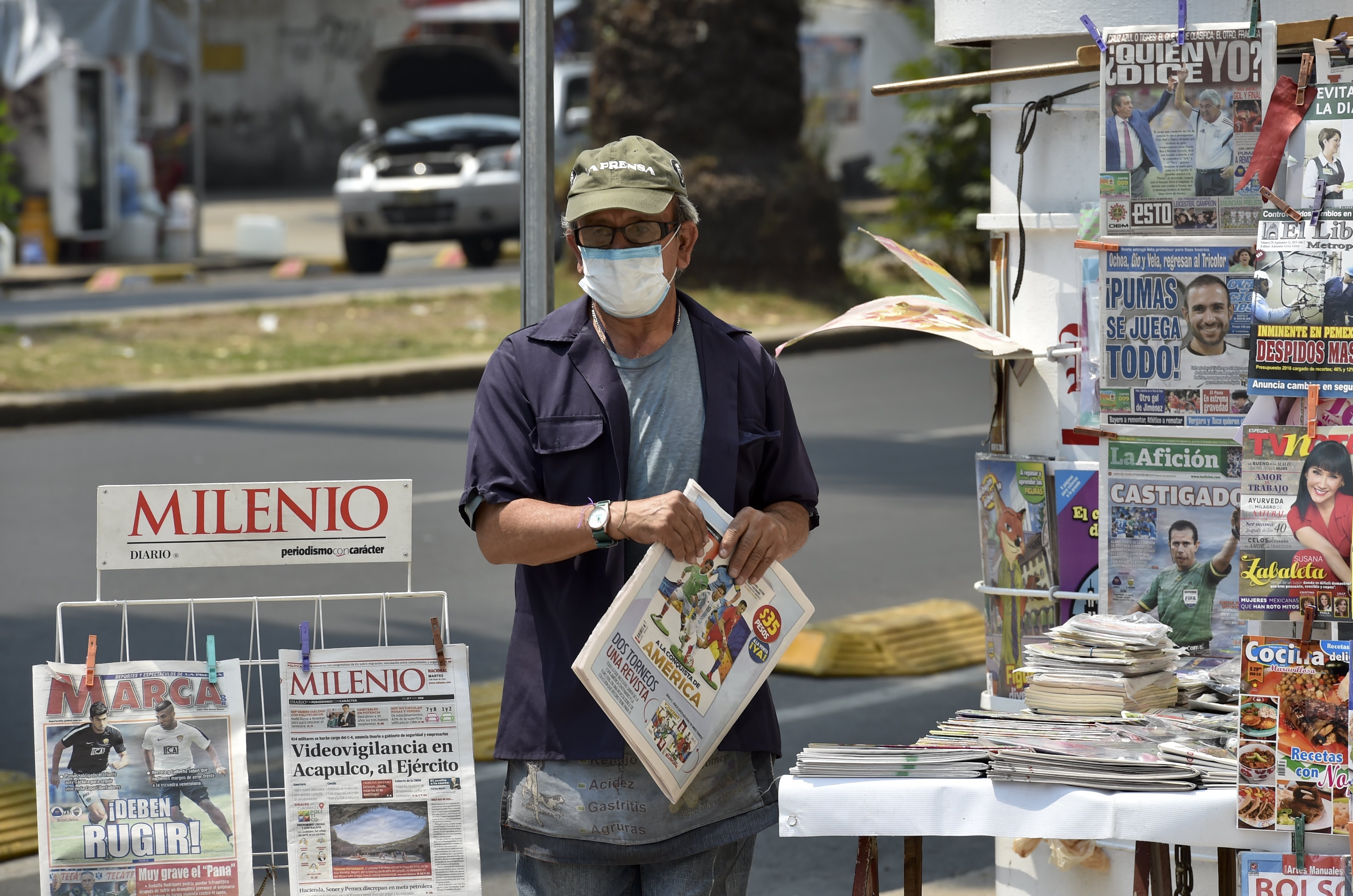 A newspapers vendor wears a surgical mask in smog-covered Mexico City on May 3, 2016 Mexico City officials issued a new air pollution alert yesterday, meaning that 40 percent of vehicles will be banned on Tuesday, while industries will be required to cut emissions. The alarm was raised after ozone levels reached 161 points, above the 150 level. The threshold was lowered from 190 to 150 last month. / AFP PHOTO / YURI CORTEZ