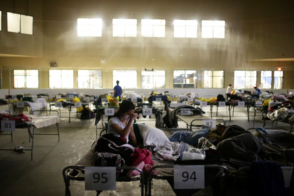 Tyra Abo sits on a cot at a makeshift evacuee center in Lac la Biche, Alberta on May 5, 2016, after fleeing forest fires north of Fort McMurray. Raging wildfires pressed in on the Canadian oil city of Fort McMurray Thursday after more than 80,000 people were forced to flee, abandoning fire-gutted neighborhoods in a chaotic evacuation. No casualties have been reported from the monster blaze, which swept across Alberta's oil sands region driven by strong winds and hot, dry weather. / AFP PHOTO / Cole Burston