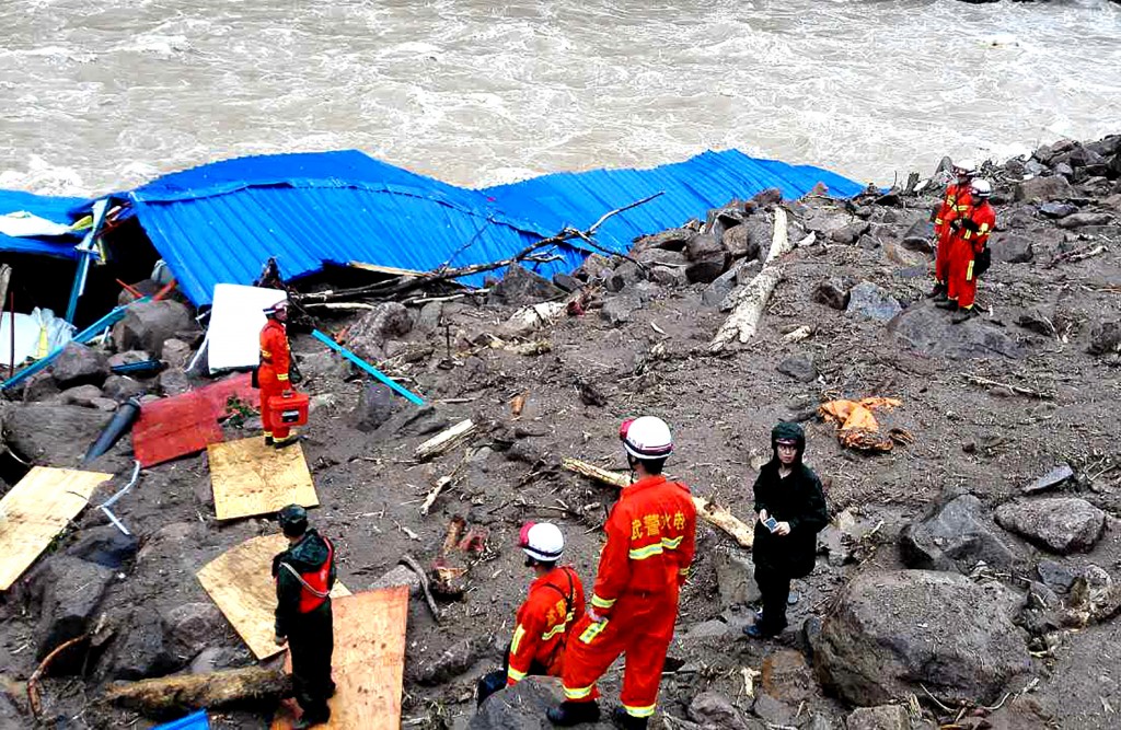 Rescuers search for survivors in the wreckage of a shelter after it was hit by a landslide in Taining County, in China's eastern Fujian province on May 8, 2016. Thirty-four construction workers are missing after the landslide buried the temporary shelter. / AFP PHOTO / STR / China OUT