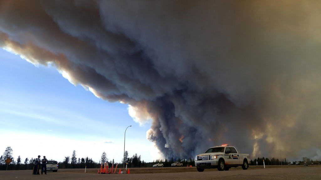 In this image released by the Alberta Royal Canadian Mounted Police (RCMP), members of the RCMP monitor the Fort McMurray Wildfire, on May 7, 2016 in Fort McMurray, Canada. The ferocious wildfire wreaking havoc in Canada doubled in size and officials warned that the situation in the parched Alberta oil sands region was "unpredictable and dangerous." "This remains a big, out of control, dangerous fire," Public Safety Minister Ralph Goodale said of the raging inferno bigger than London that forced the evacuation of the city of Fort McMurray. Winds were pushing the flames east of the epicenter around the oil city late Saturday, as nearly all 25,000 people who were still trapped to the north finally left town, either via airlift or convoys on the roads. The wildfire had doubled in size in one day, covering more than 200,000 hectares (494,000 acres) by midnight and continuing to grow, the Alberta Emergency Management Agency said in an update late May 6. / AFP PHOTO / Alberta RCMP / RCMP Alberta / RESTRICTED TO EDITORIAL USE - MANDATORY CREDIT "AFP PHOTO / ALBERTA RCMP/ HO" - NO MARKETING NO ADVERTISING CAMPAIGNS - DISTRIBUTED AS A SERVICE TO CLIENTS