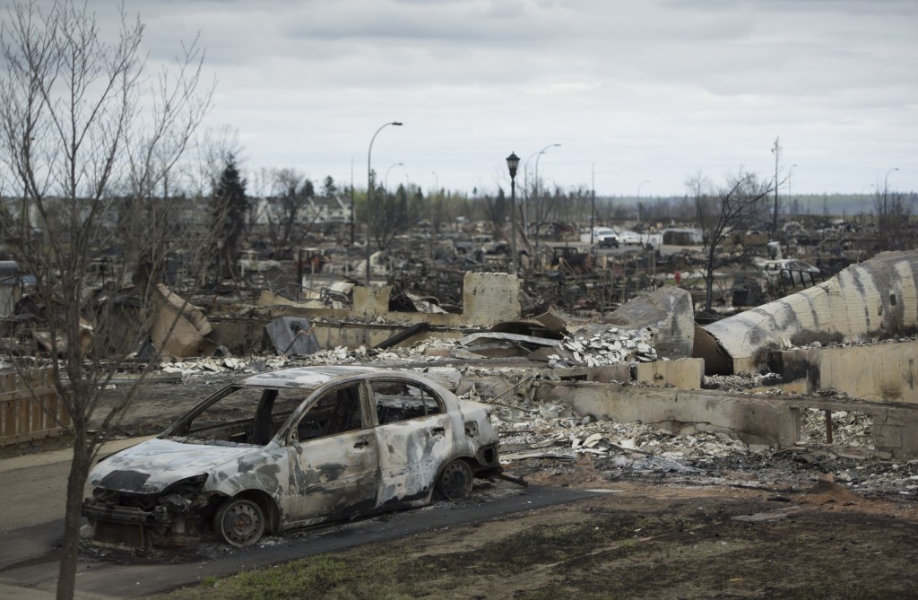 A burnt out pick up truck is seen in the driveway of a burnt down home in the Beacon Hill neighbourhood in Fort McMurray, Alberta, Monday, May 9, 2016. Authorities battling a forest fire in Canada looked to Mother Nature for more help May 9, as cooling temperatures and rain slowed the spread of the blaze that had forced the evacuation of an entire city. / AFP PHOTO / POOL / JONATHAN HAYWARD