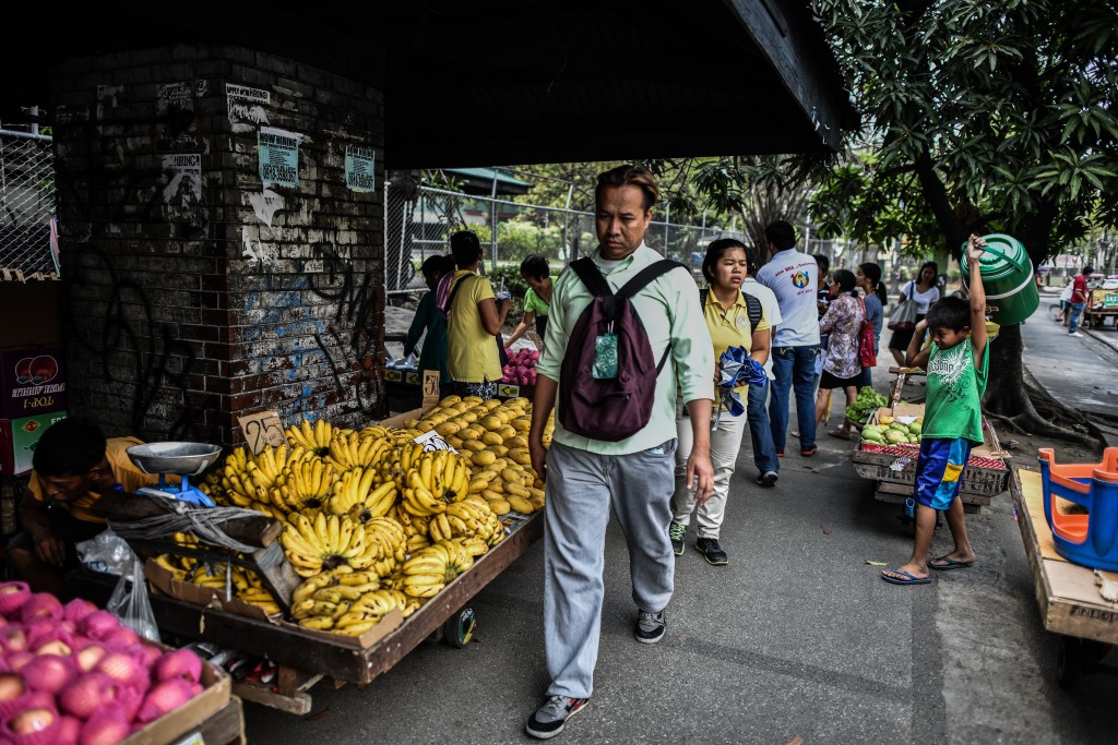 Filipinos walk past roadside stalls in Manila on May 10, 2016, a day after the country went to the polls in the presidential election. Anti-establishment firebrand Rodrigo Duterte stormed to a huge win in the Philippine presidential elections, according to poll monitor data released Tuesday, after an incendiary campaign dominated by his profanity-laced vows to kill criminals. / AFP PHOTO / MOHD RASFAN