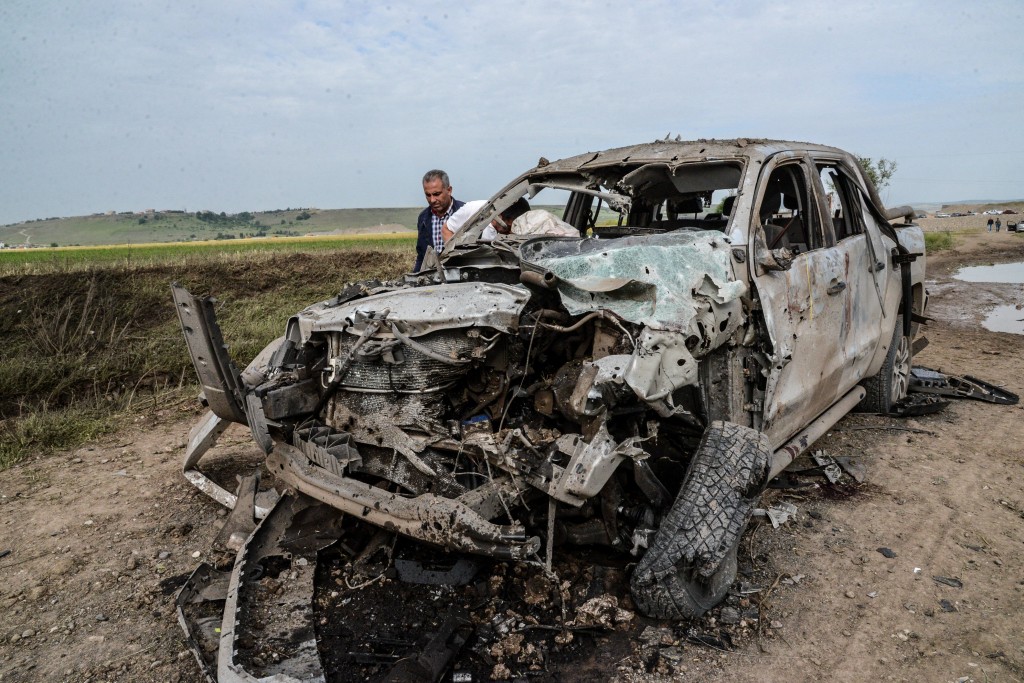 A man walks past a burnt car after a powerful blast on May 13, 2016 in the area of Sarikamis on the outskirts of the majority Kurdish city of Diyarbakir. A powerful blast that shook an area near the Turkish city of Diyarbakir on May 12 killed four "bombmakers" and injured at least 10 other people, the Interior ministry said. / AFP PHOTO / ILYAS AKENGIN