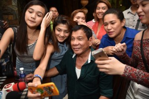 Philippines' President-elect Rodrigo Duterte, poses for selfie pictures with supporters, after speaking to the media for the first time since he claimed victory in the presidential election, at a restaurant in Davao City, on the southern island of Mindanao on May 15, 2016. Duterte vowed on May 15 to reintroduce capital punishment and give security forces "shoot-to-kill" orders. / AFP PHOTO / TED ALJIBE