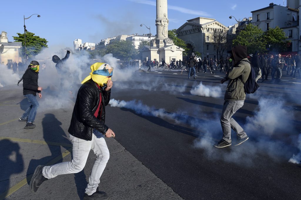 People run from tear gas during clashes between French anti riot police and protesters during the traditional May Day demonstration in Paris on May 1, 2016. AFP PHOTO / MIGUEL MEDINA / AFP PHOTO / MIGUEL MEDINA