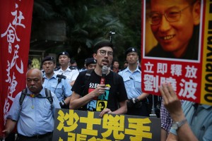 Avery Ng (C), Chairperson of the League of Social Democrats, talks to a crowd outside the Central Government Headquarters in Hong Kong on May 17, 2016, in a protest coinciding with the visit of Zhang Dejiang - who chairs China's communist-controlled legislature - to the territory. One of China's most powerful officials said he would listen to political demands from Hongkongers in a conciliatory start to a visit May 17 that has stirred anger in a city resentful of Beijing's tightening grip. / AFP PHOTO / ISAAC LAWRENCE