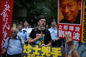 Avery Ng (C), Chairperson of the League of Social Democrats, talks to a crowd outside the Central Government Headquarters in Hong Kong on May 17, 2016, in a protest coinciding with the visit of Zhang Dejiang - who chairs China's communist-controlled legislature - to the territory.  One of China's most powerful officials said he would listen to political demands from Hongkongers in a conciliatory start to a visit May 17 that has stirred anger in a city resentful of Beijing's tightening grip. / AFP PHOTO / ISAAC LAWRENCE