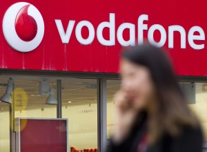 (FILES) This file photo taken on March 17, 2014 shows a woman walking past a branch of Vodafone in London on March 17, 2014. British telecoms giant Vodafone on May 17, 2016 posted its first annual rise in operating profits in eight years, boosted by growth in Europe and emerging markets. Earnings before interest, tax, depreciation and amortisation (EBITDA) grew 2.7 percent to £11.6 billion ($16.7 billion, 14.7 billion euros) in the year to March, Vodafone said in a results statement. / AFP PHOTO / JUSTIN TALLIS