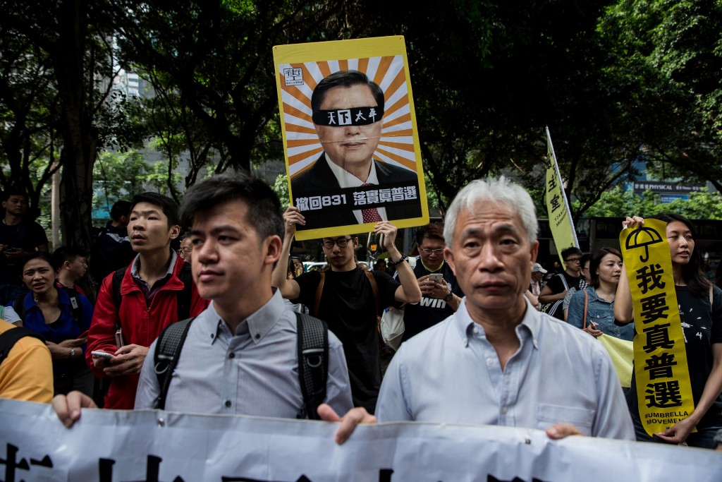 Demonstrators march during a pro-democracy protest in Hong Kong on May 18, 2016, during the second day of a visit by China's National People's Congress (NPC) Standing Committee Chairman Zhang Dejiang (on placard). One of China's most powerful officials arrived in Hong Kong on May 17 in an attempt to build bridges in the divided city, but the trip has already stirred anger among opponents. / AFP PHOTO / DALE DE LA REY